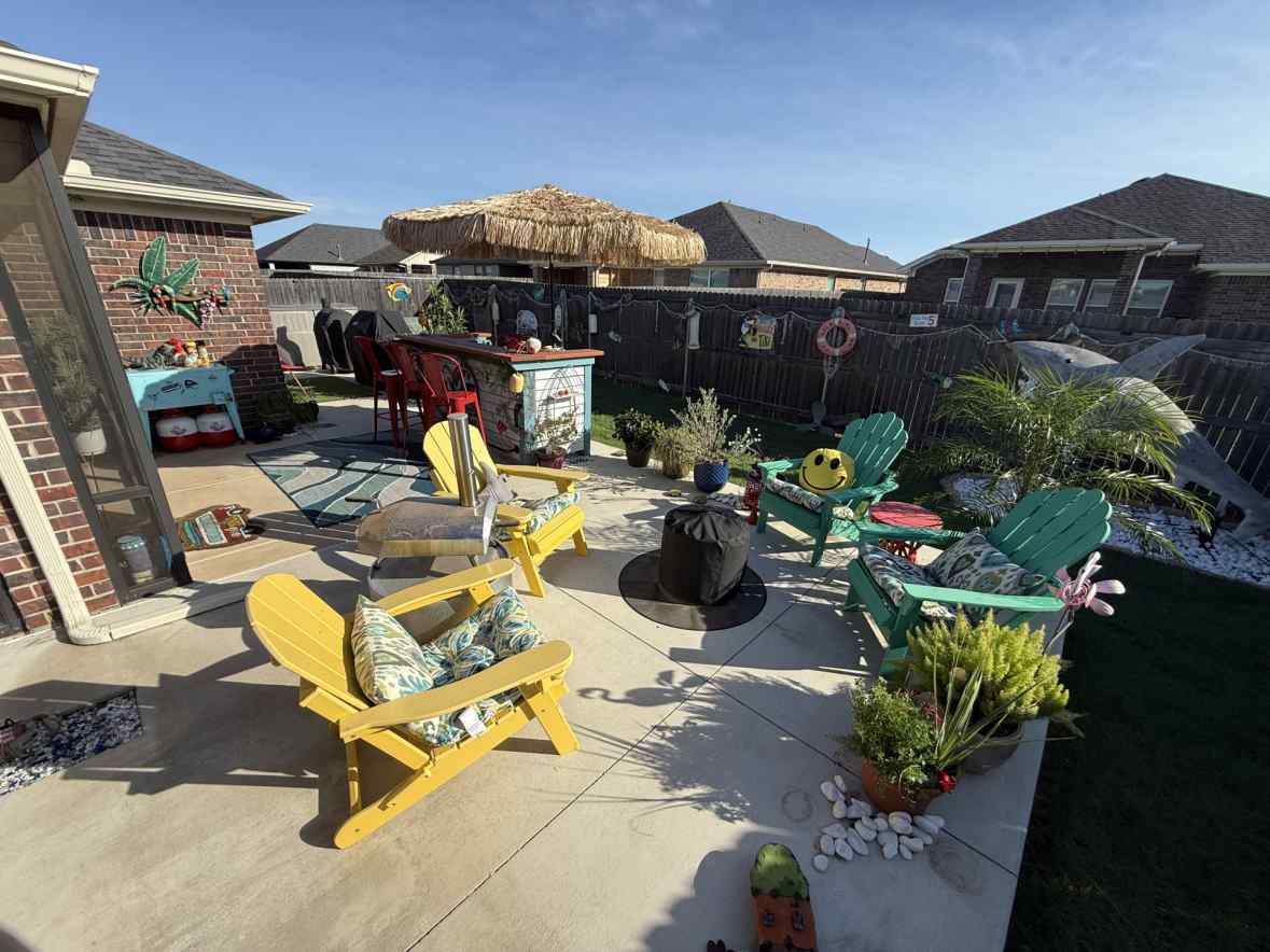 Rusty's full backyard tiki bar setup with thatched umbrella, teal bar, red stools, and the metal shark sculpture in the corner